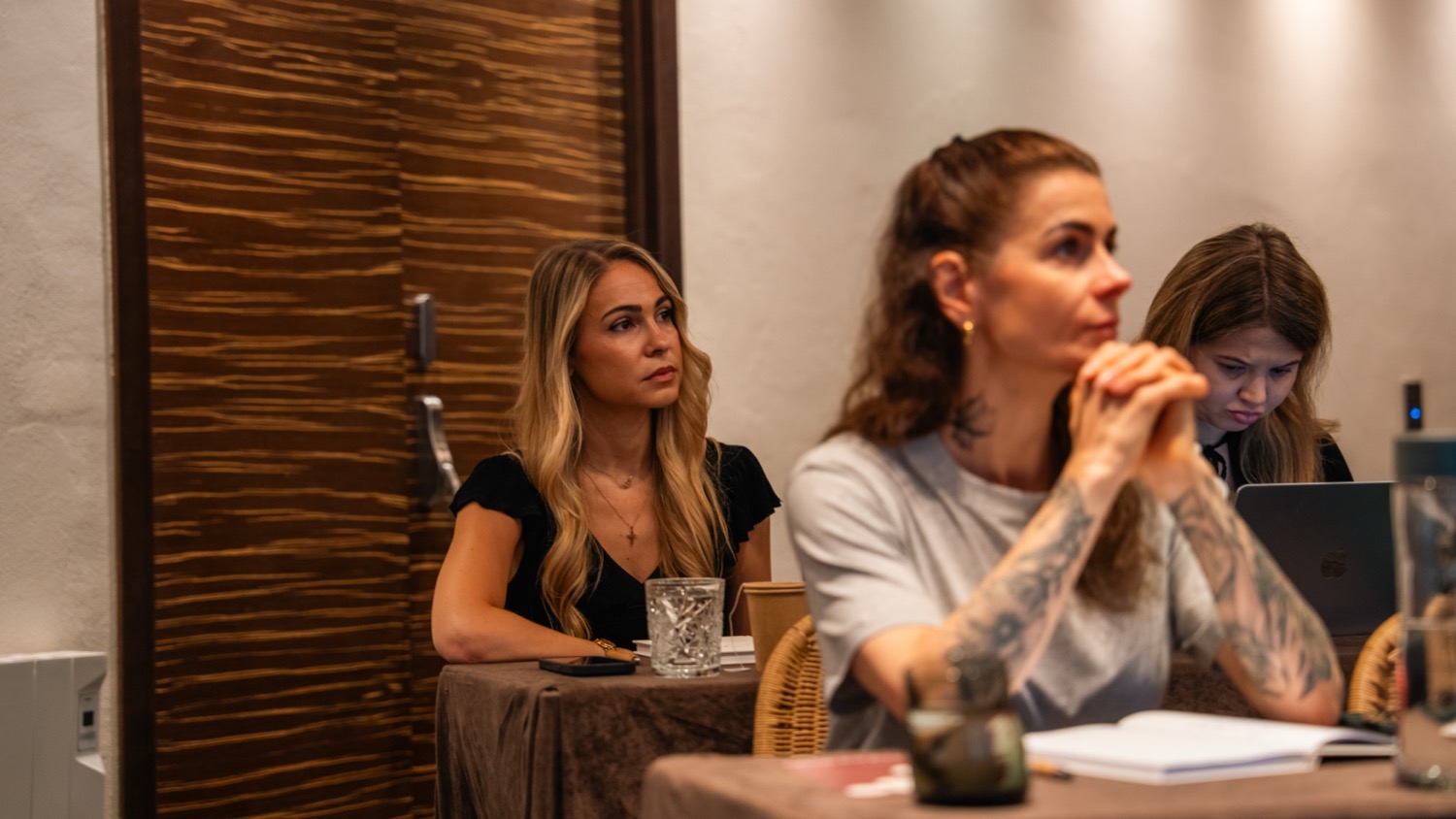 Women seated at tables, listening intently to a session